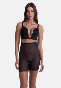 Svarta sömlösa kompressionsshorts tillverkade av genomskinligt material, med hög midja och skärning till mitten av låret, designade för en smidig täckning.