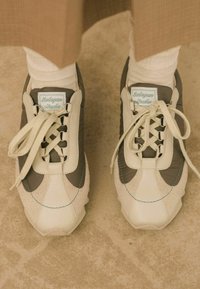 Sneakers con parte superiore in materiali misti caratterizzate da pelle beige e accenti grigi, punta rotonda e lacci crema. Etichetta "Balagan Studio" sul tallone.
