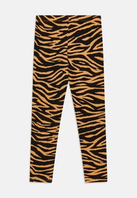 Leggingi s tigerjemi vzorom, ki prikazuje črno in oranžno barvo, izdelani iz mehke, raztegljive tkanine in taperiziranega kroja za udobno prileganje.