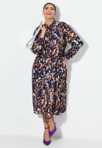 Abito a maniche lunghe con bottoni in stampa leopardata multicolore che presenta tonalità di blu, arancione e viola. Include una vita legata e una gonna fluida.