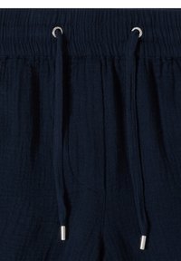 Taille de pantalon en tissu texturé bleu marine avec élastique et deux cordons dotés d'embouts métalliques et d'œillets.