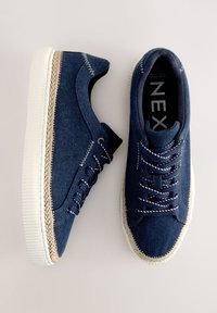 Blå denim-sneakers med flettet jutedetalje på sålen, flade snørebånd og kontrastsyninger. Indeni er der et trykt brandlogo.