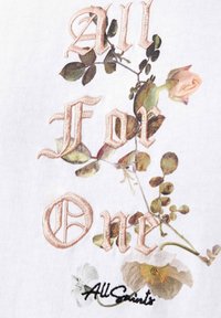 Delicate roze geborduurde tekst "All For One" verwikkeld met groene bladerenrank en kleine pastelkleurige bloemen op witte stof.