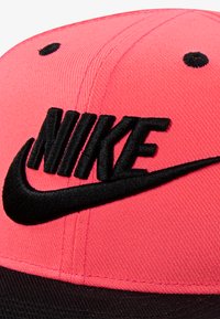 Ροζ υφασμάτινο καπέλο με μαύρο κεντημένο λογότυπο «Nike» και σχέδιο Swoosh, με δομημένο σχήμα και υφή επιφάνειας.