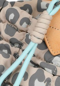 Tissu texturé beige avec motif animal gris, doté d'un cordon de serrage bleu aqua et d'accents en cuir beige clair.
