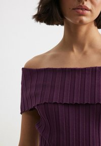 Fioletowa sukienka bez ramiączek z prążkowaną fakturą i falbaniastym dołem. Posiada dopasowany krój, który podkreśla sylwetkę.