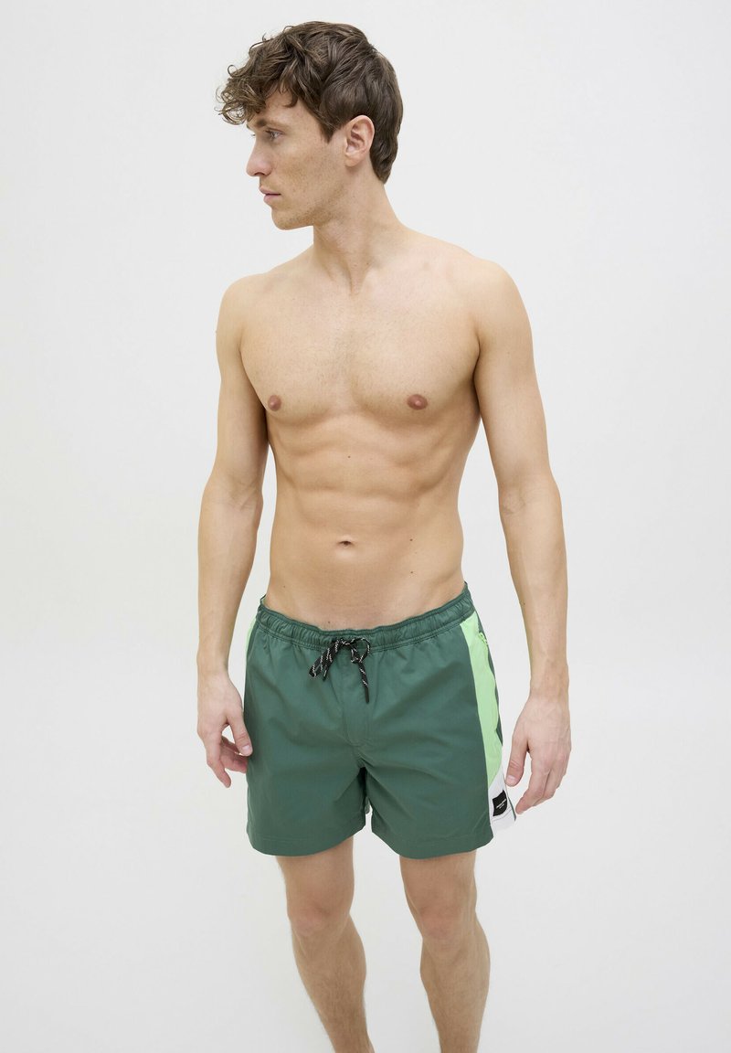 Groene zwembroek met een trekkoordsluiting, voorzien van een zijpaneel in felgroen, met een gladde textuur en een standaard pasvorm.