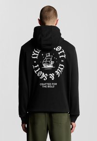 Felpa nera con grafica bianca di una nave e testo sulla schiena. Presenta un cappuccio con coulisse e polsini a costine. Tessuto morbido.