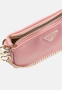Rosa synthetische Stofftasche mit goldenen Beschlägen, ausgestattet mit einem Reißverschluss und einer Kettenriemen. Auffälliges dreieckiges Logo-Detail auf der Vorderseite.