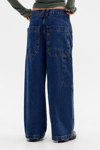 Wide-leg blue denim jeans feature a high waist, two back pockets, and subtle branding. The fabric has a textured finish.