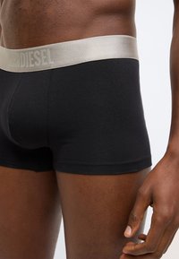 Fekete pamut boxeralsó puha, fémes ezüstös derékpánttal, amelyen a "DIESEL" logó található. Sima textúra és testhezálló kialakítás.