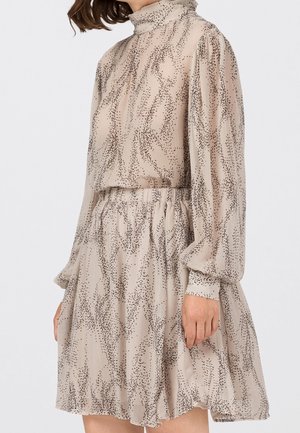 Robe beige avec motif de points abstraits noirs, col haut, manches bouffantes longues et taille élastique, fabriquée en tissu léger et transparent.