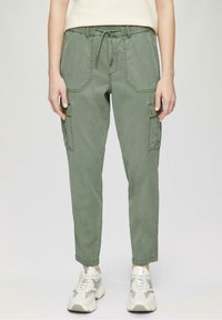 Zelené cargo kalhoty s elastickým pasem, které mají boční kapsy a štíhlý střih. Tkanina má jemnou strukturu.