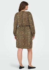 Lietus svārki ar leoparda rakstu bēšā un melnā krāsā, garām piedurknēm, izceltu jostas vietu, līdz ceļiem, mīksts audums, melnas plakanas kurpes.