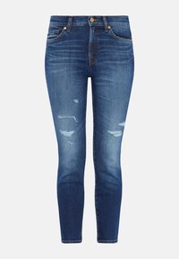 Jeans ajustados de mezclilla azul en tono desgastado con detalles rasgados. Presentan un diseño clásico de cinco bolsillos y un cierre de botón en la cintura.
