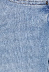 Tissu en denim bleu clair avec une poche en haut et de subtiles lignes de décoloration verticales près du centre supérieur.