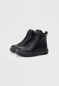 Zapatillas altas negras de cuero texturizado, con suela de goma, cierre de cordones en la parte delantera y una lengüeta en la parte trasera.