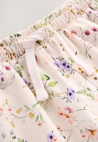 Szorty w kwiatowy wzór z miękkiej tkaniny, z jasnoróżową bazą oraz różnorodnymi kolorowymi kwiatami. Elastyczny pas z regulowanym sznurkiem.