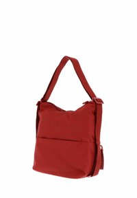 Sac à épaule en tissu rouge avec une surface texturée, bandoulière réglable et poche avant. Design incurvé et fermeture éclair en haut.