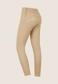 Leggings beige con vita alta, dotati di una cerniera sul retro, design senza cuciture e cuciture definite per un fit e una silhouette liscia.