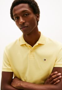 Κιτρινό πόλο μπλουζάκι από βαμβάκι με υφή. Διαθέτει τρία κουμπιά και ένα μικρό λογότυπο στο αριστερό στήθος.