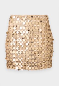 Mini-jupe à sequins dorés, ornée de disques métalliques ronds cousus sur une base en maille, créant une surface réfléchissante et texturée.