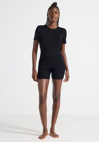 Svart bomull t-shirt med korta ärmar i kombination med svarta bomullsshorts. Enkelt mönster, slät textur, figurnära passform.