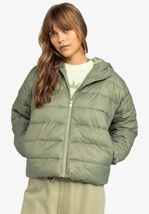 Puffer jacket in olive green with quilted design and hood. Features a front zipper and slightly cropped fit, paired with a light green top.