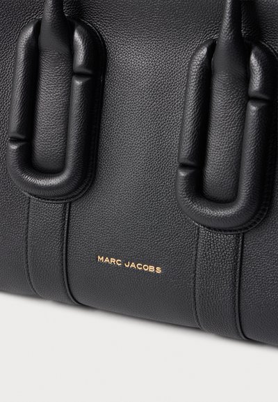 Sac en cuir noir texturé avec poignées rembourrées et logo Marc Jacobs doré centré près du bas.