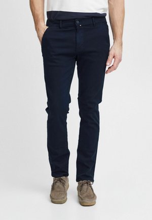 Dunkelblaue Chinos aus Baumwolle mit slim fit Design, ausgestattet mit Gürtelschlaufen, Fronttaschen und einem Knopfverschluss. Glatte Textur.