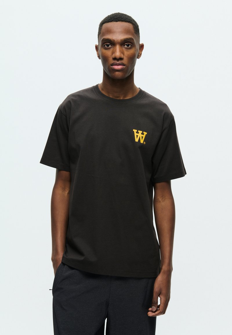 Black cotton t-shirt featuring a yellow "W" logo on the left chest. Classic fit with short sleeves and crew neck design.