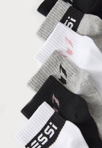Cinque paia di calzini di cotone in nero, grigio e bianco. Ognuno ha una texture a coste e loghi stampati in colori contrastanti sui polsini.