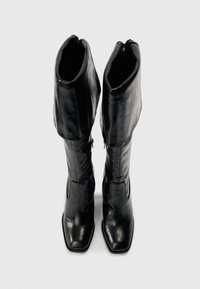 Black leather knee-high boots with a slouchy shaft, squared toe, and zip closure on the inner side. Smooth texture and glossy finish.