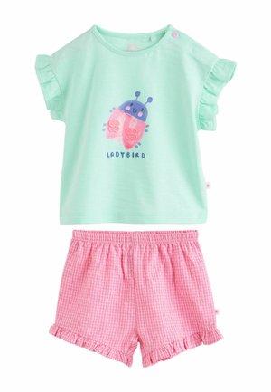 Mündiroheline lühikeste varrukatega pluus lepatriinu mustriga ja volditud varrukatega, sobitatud roosade ruudulise mustriga lühikeste pükstega, millel on volditud äär.