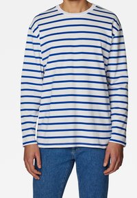 Långärmad randig skjorta i vitt med blå horisontella linjer, rund halsringning, mjukt tyg, avslappnad passform, parat med blå jeans.