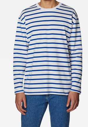 Langärmeliges gestreiftes Hemd in Weiß mit blauen horizontalen Linien, runder Ausschnitt, weicher Stoff, lockere Passform, kombiniert mit blauen Jeans.