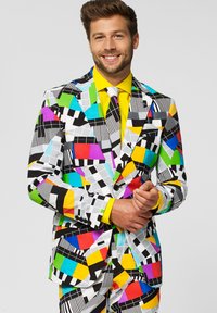 Colorful patterned suit with geometric designs in black, white, red, blue, green, yellow, and purple. Features a bright yellow shirt and tie.