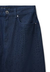 Jeans in denim blu scuro con un design classico, dotati di tasca frontale e decorati con piccoli borchie nere disposte in un motivo a pois.