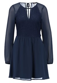 Laivansinis mekko, jossa on läpinäkyvät pitkät hihat, pitsinen yläosa, V-pääntie ja solmimiskaulus takana. Virtaava hame kerätyllä vyötäröllä.