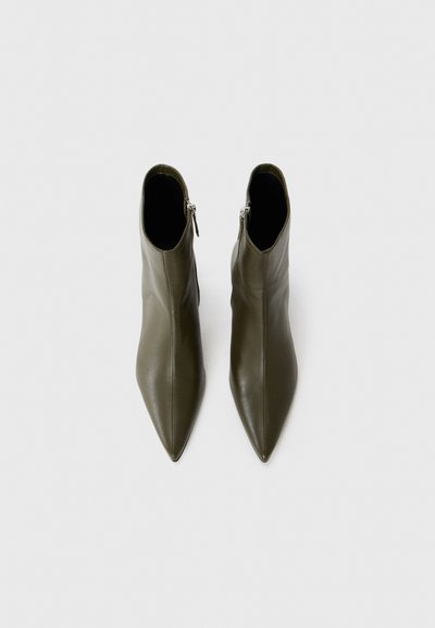 Stivali alla caviglia verde oliva con punta, realizzati in pelle liscia e dotati di una zip laterale, caratterizzati da un design elegante e aderente.