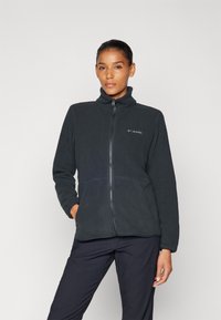 Dark gray fleece jacket featuring a high collar, full zipper, and side pockets. Textured fabric with subtle branding on the left chest.
