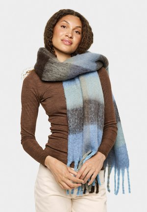 Ullscarf med en gradient av blå, grå och beige ränder, med fransar i ändarna och en mjuk textur. Bärs runt halsen.