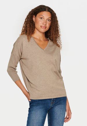 Beige, lichtgewicht gebreide trui met V-hals en driekwartmouwen, gecombineerd met denim jeans. Glad oppervlak, relaxte pasvorm.