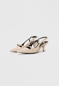 Beige leather slingback heels with a pointed toe, cut-out design, small buckle detail, and a 2.5-inch tapered heel.