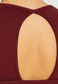 Bordeaux athletic top med en udskåret rygdesign, glat tekstur og minimale sydetaljer ved halsudskæringen og ærmegabene.
