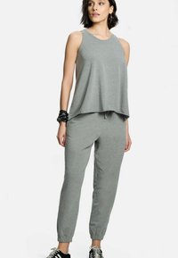 Szary top na ramiączkach w luźnym fasonie oraz szare spodnie dresowe z elastycznymi mankietami. Miękka tkanina o gładkiej fakturze, z elastycznym paskiem w talii.