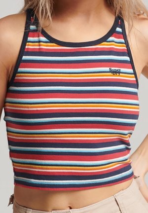 Kobieta w bezrękawniku z wielokolorowymi, poziomymi paskami, wykończonym czarną lamówką i małym logo "Superdry" na piersi.