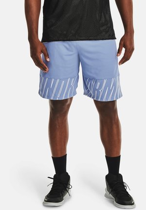 Mand iført lyseblå løbetights med hvid Under Armour-logo på kanten, sort nettrøje, sorte sokker og sorte sneakers, der står.