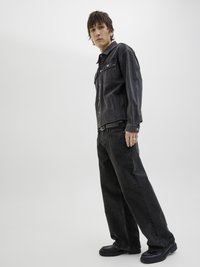 Giacca di jeans nera con tasche frontali e jeans neri a vestibilità comoda. L'outfit presenta un design semplice e una texture morbida. Le calzature nere completano il look.