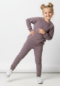 Fioletowa bluza z kapturem i dopasowane dresy wykonane z miękkiego materiału. Bluza posiada ściągacze na rękawach oraz okrągły dekolt, natomiast dresy mają elastyczny pas.